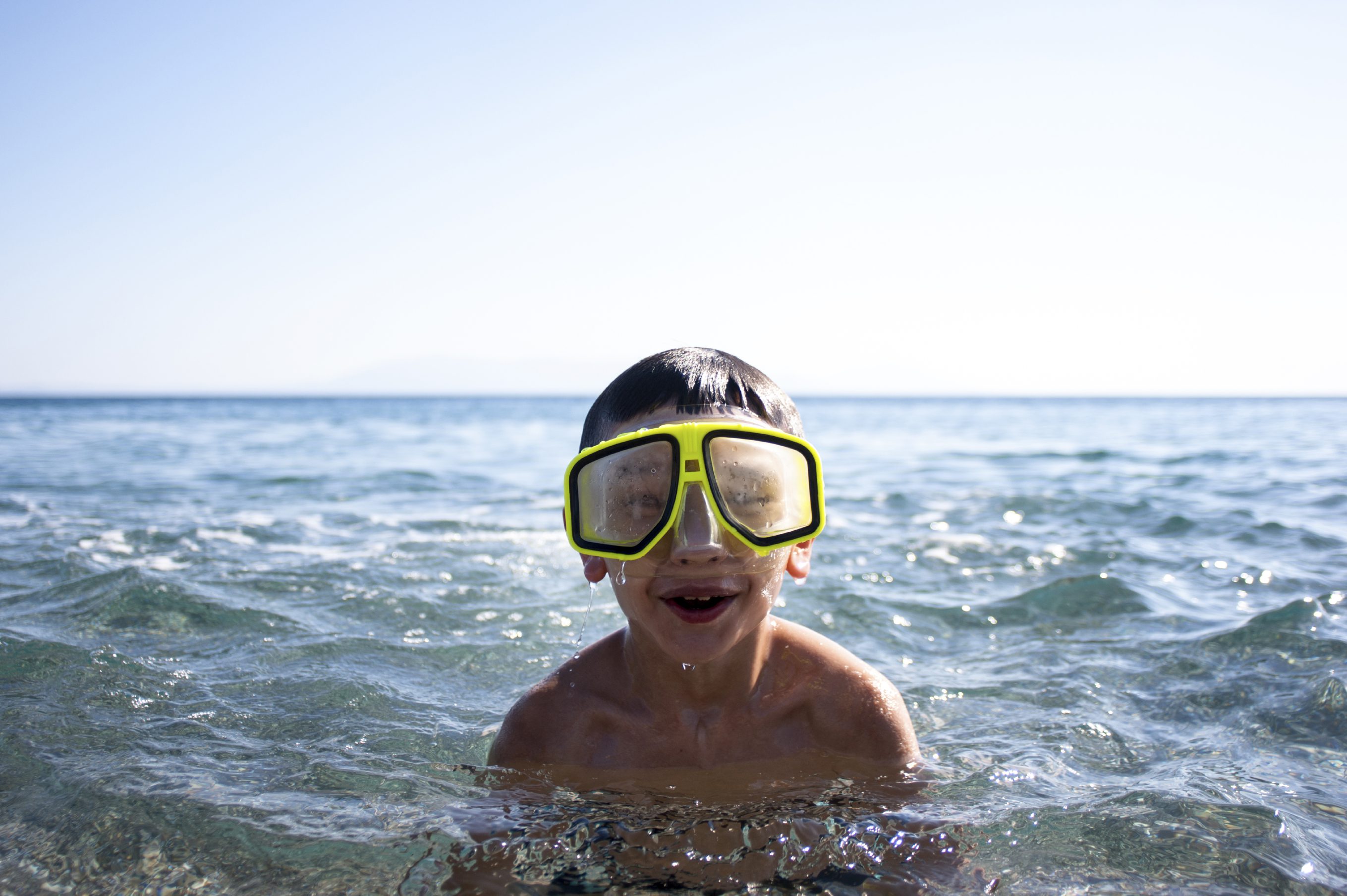 Boy with diwing goggles in the sea.