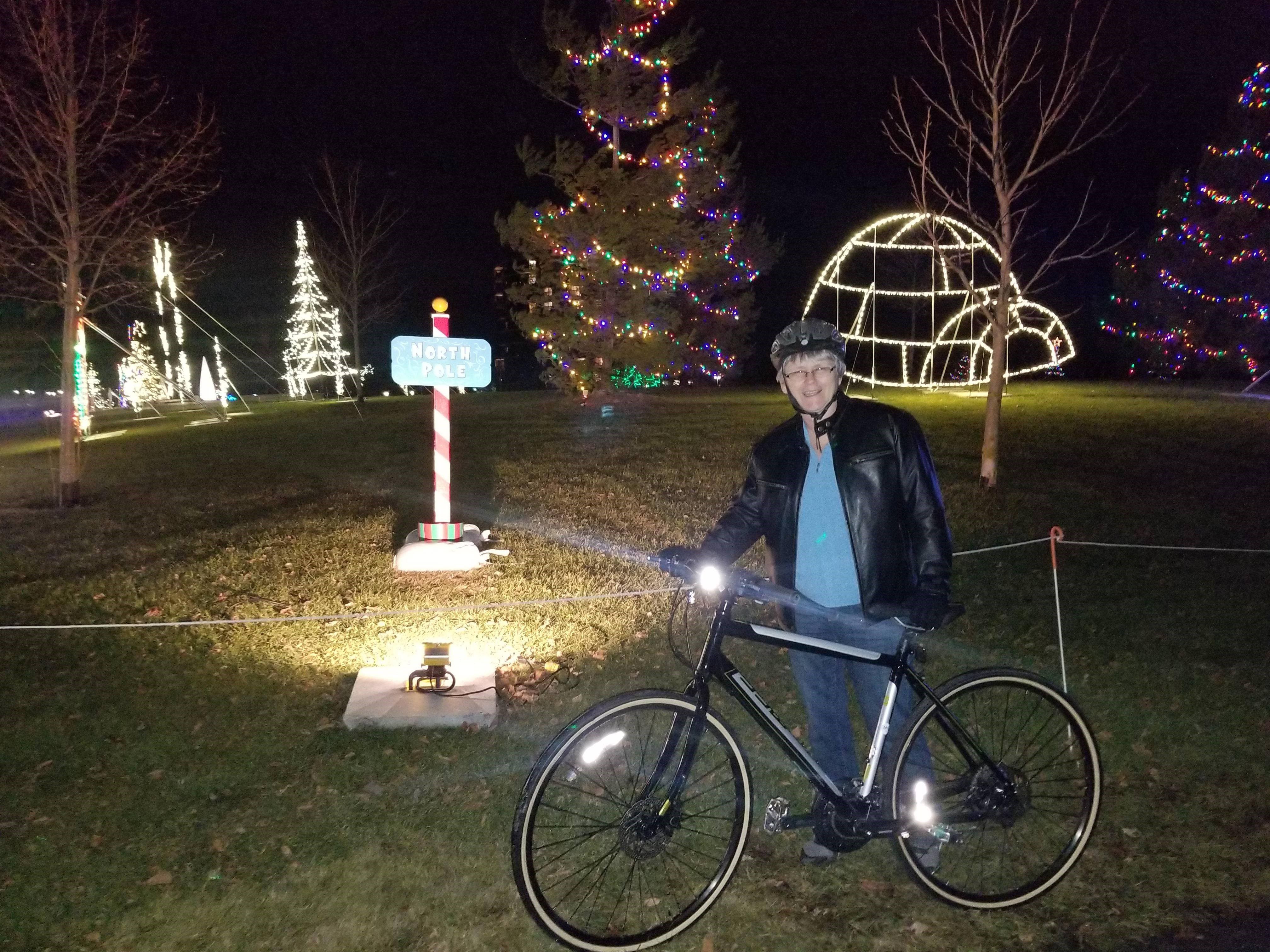 Donnah stands with her bike in front of some festive decorations