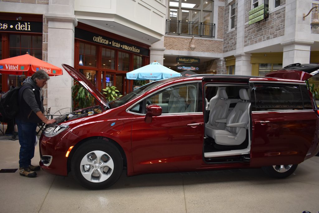The Pacifica mini-van with large sliding side-door open and a visitor looking inside