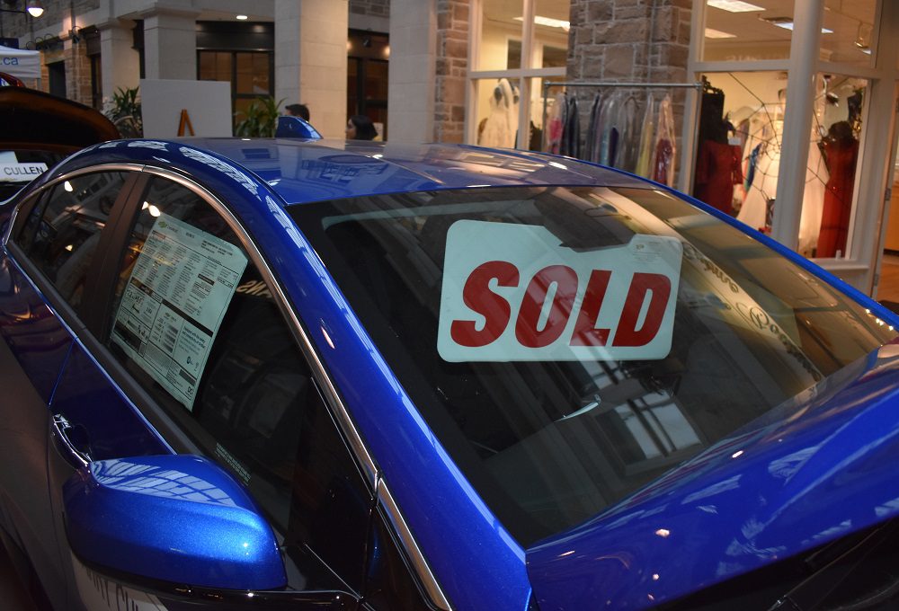 A blue electric car with a 'sold' sign in the window