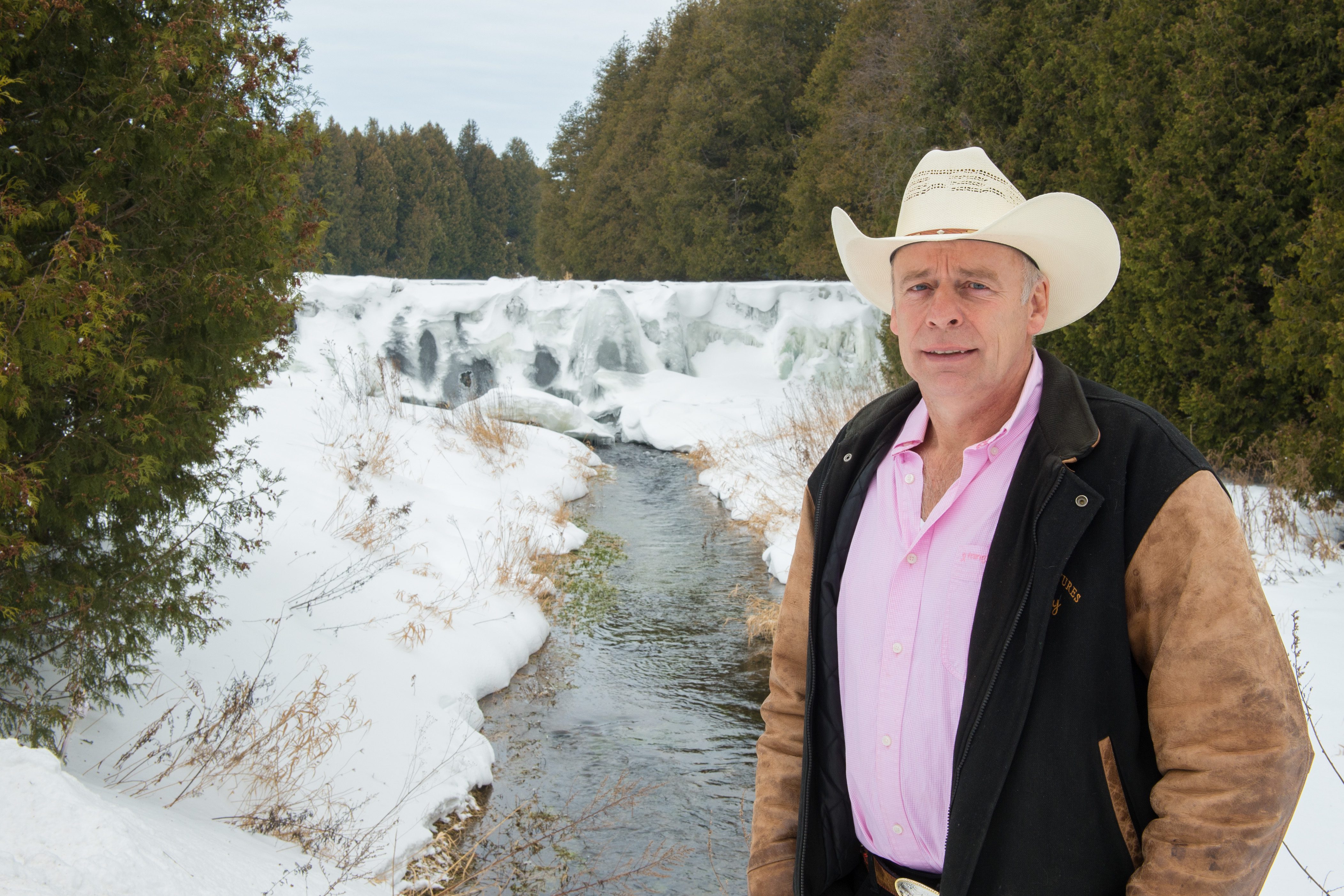 Cattle rancher Carl Cosack stands in front of a river in Melancthon Township.