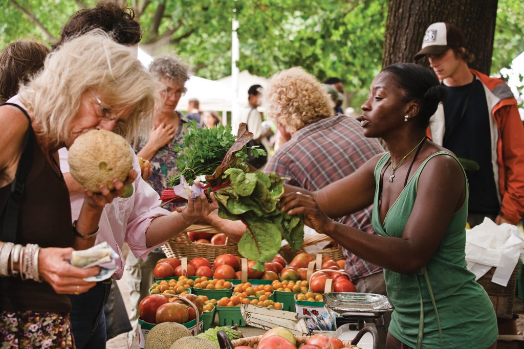 Shoppers at a bustling farmers' market in Toronto, selecting local, organic produce from Ontario organic farmer Ted Thorpe.