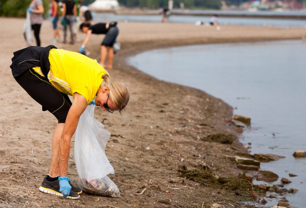 Woman picks up litter at beach cleanup