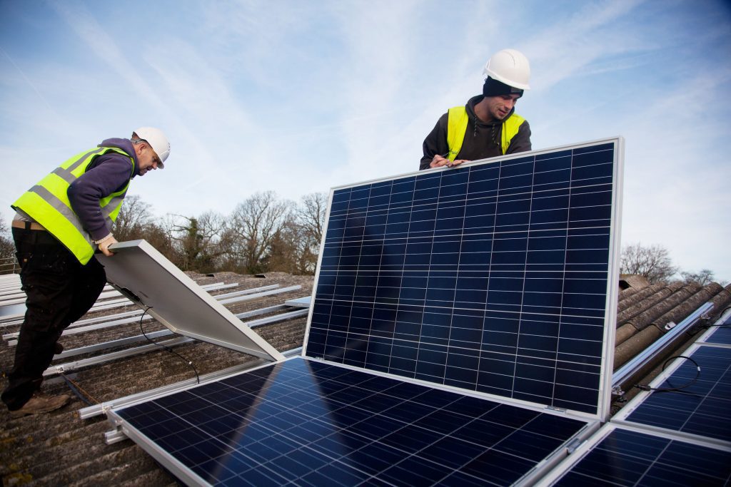 Workers install solar panels on a barn roof. Photo credit: 10 10 https://bit.ly/2S8IyJU