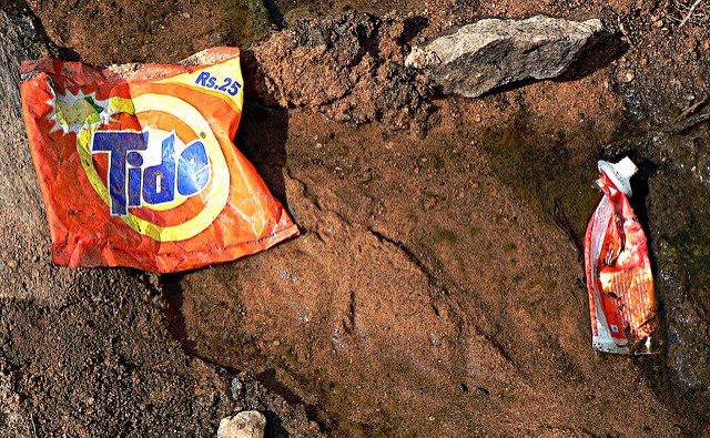 Tide packaging and toothpaste tube washed up on a beach