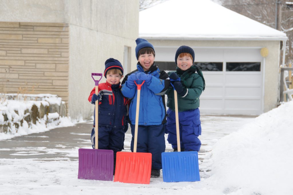 Three young boys take pride in completing a big shoveling job