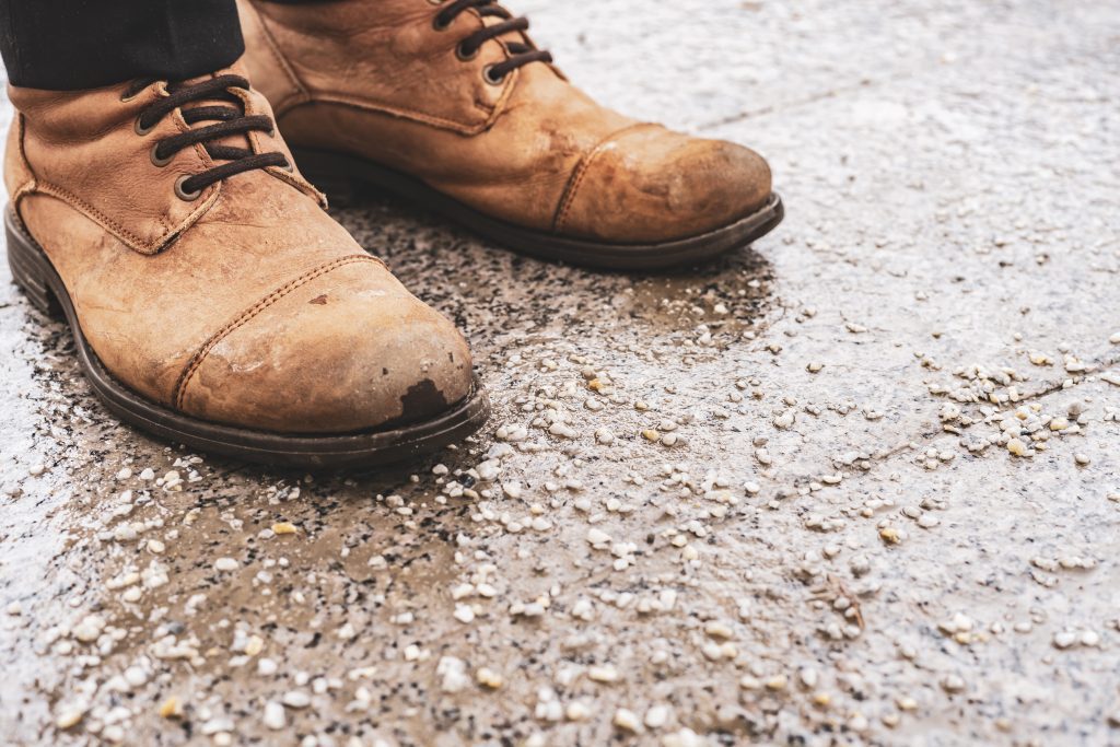 damaged persons shoes on salted pavement in the city during winter season