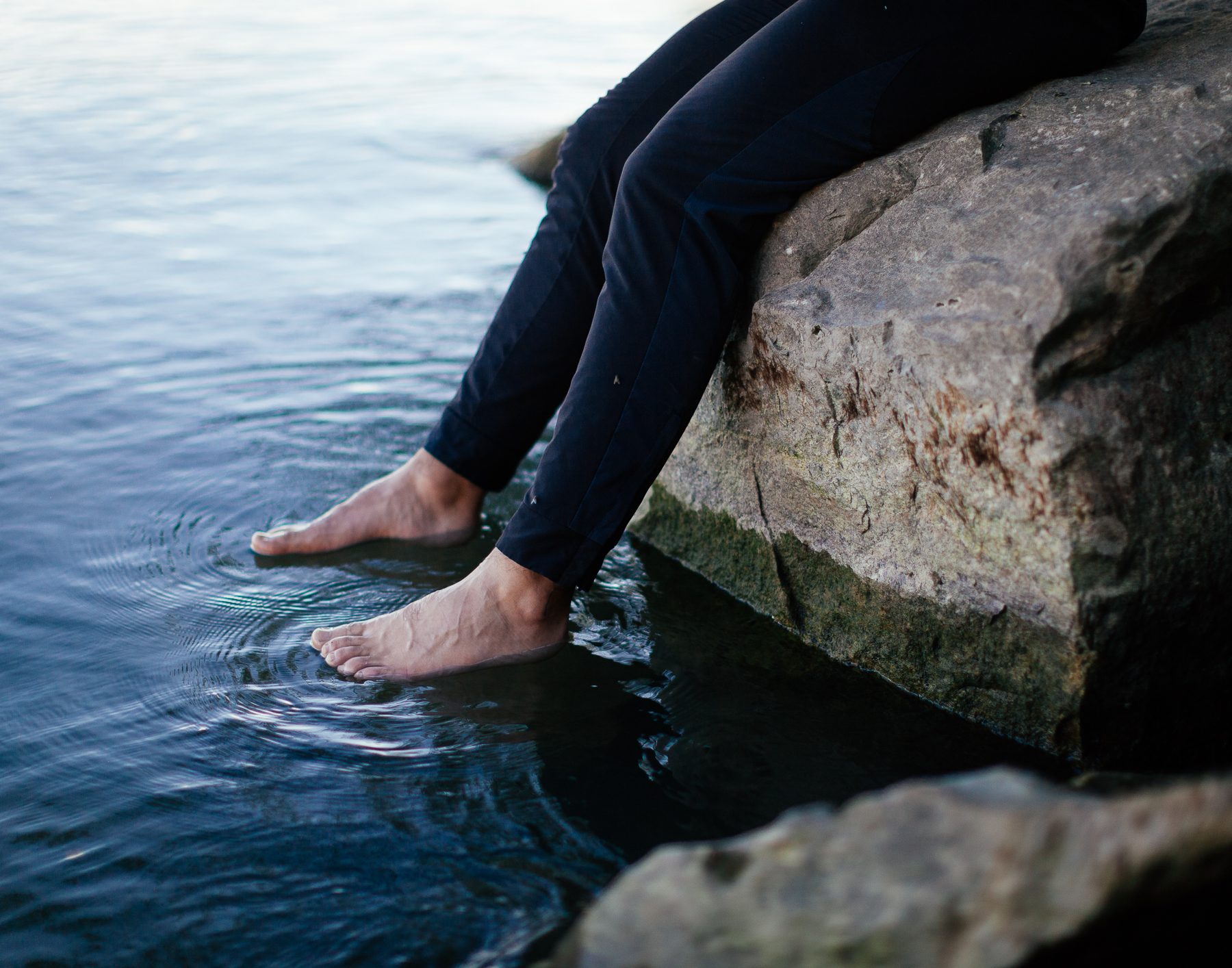 Mohamad sits on the shores of Lake Erie with his feet in the water. 