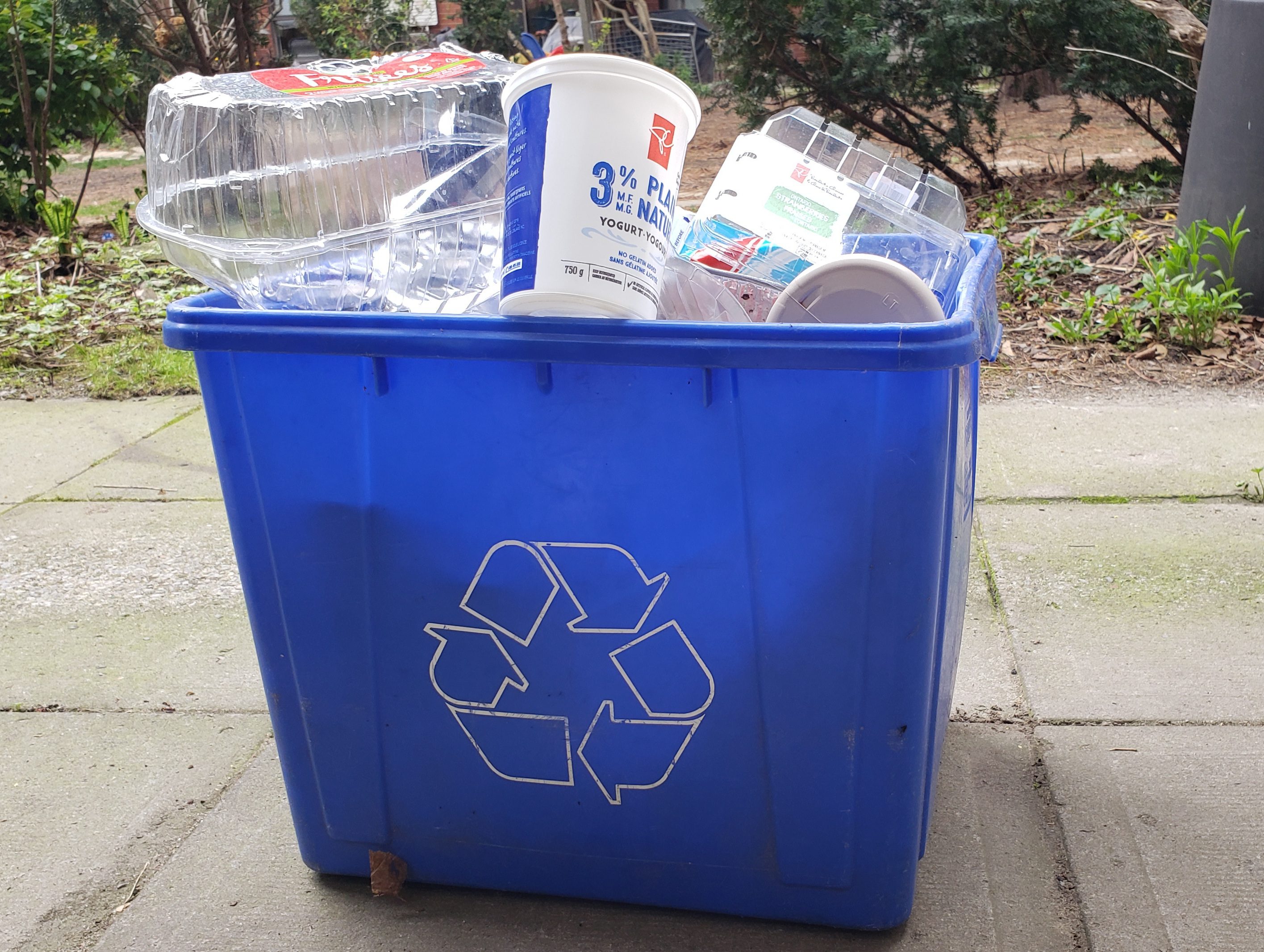 A recycling bin overflowing with plastic packaging.