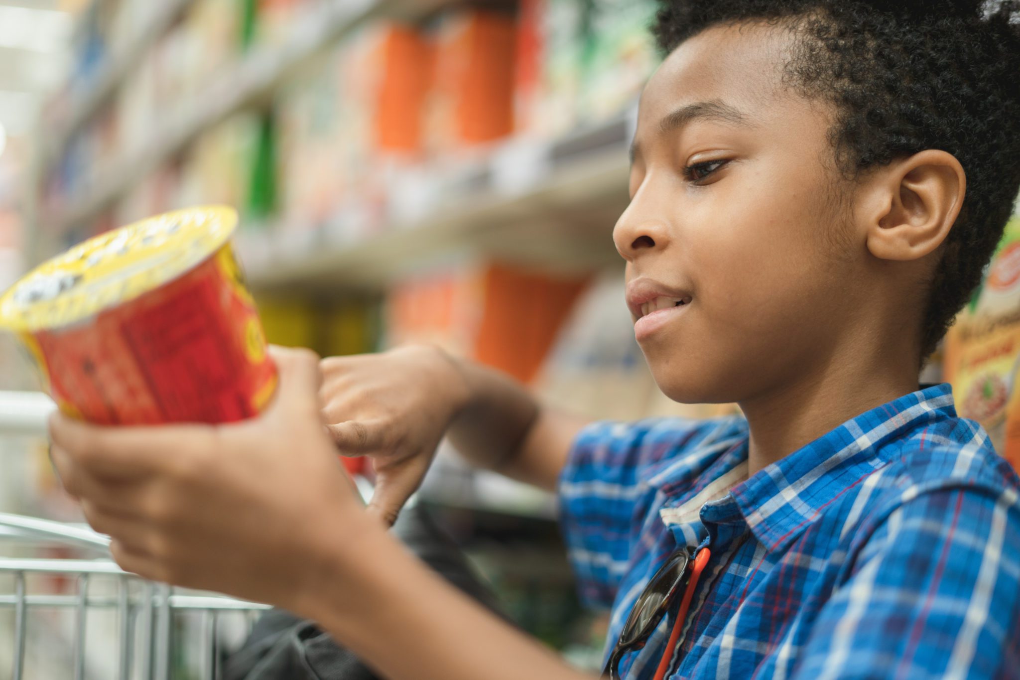 Young afro American kid reading chips label on a supermarket mal