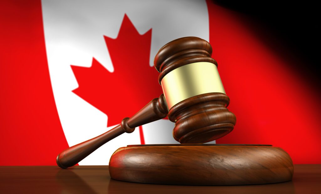 3D rendering of a gavel on a wooden desktop and the Canadian flag in background