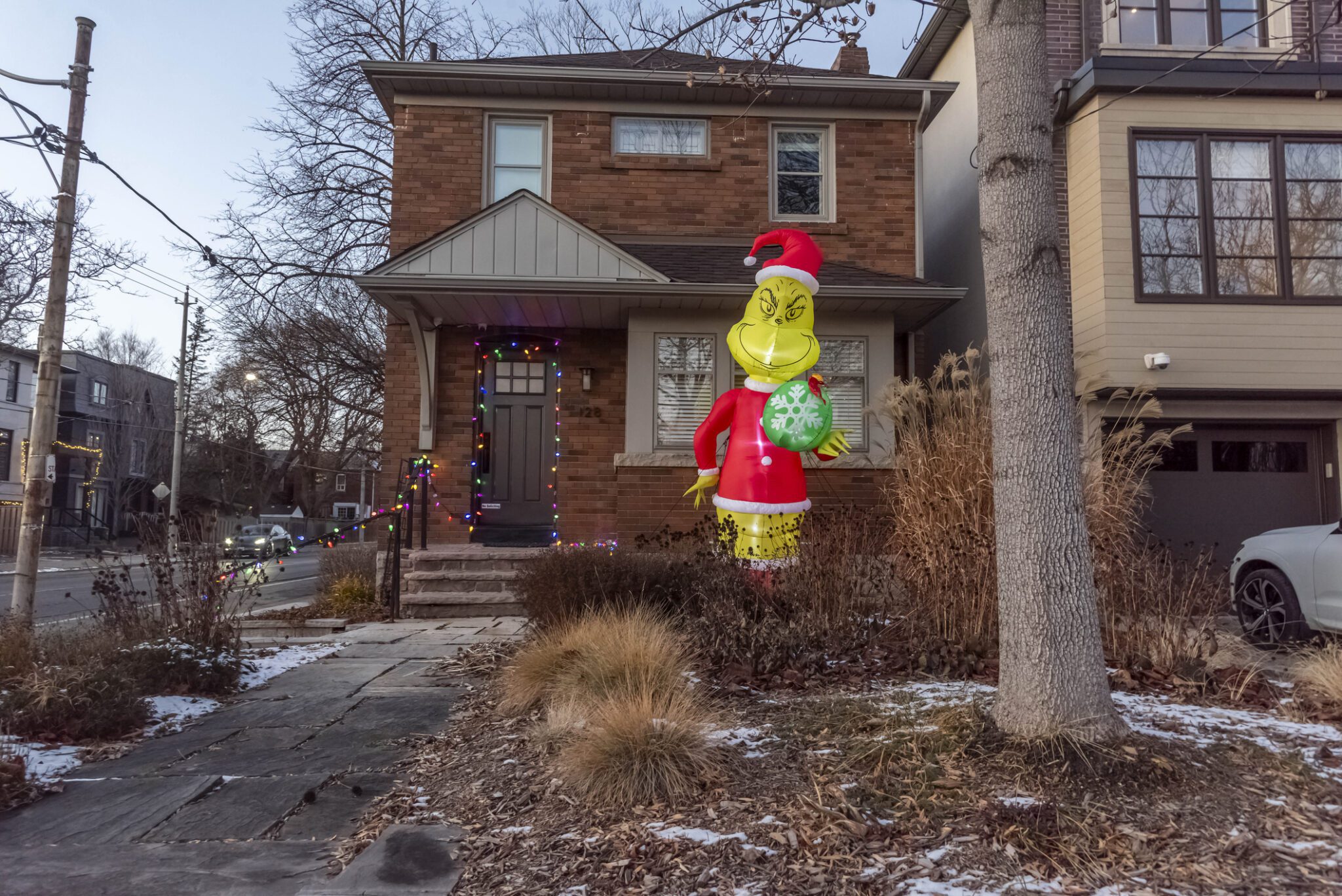 The grinch outside a home decorated for Christmas