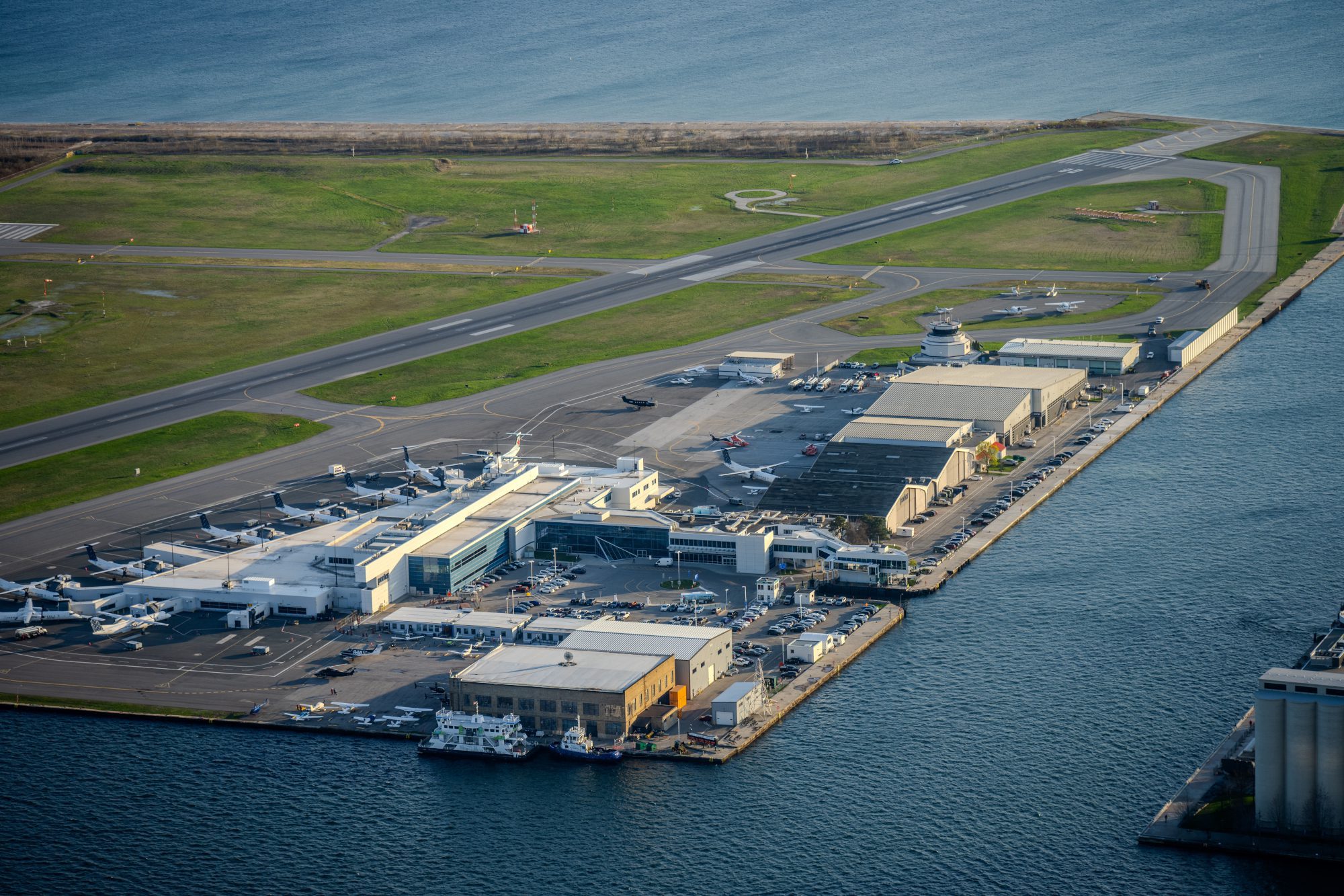Passenger terminal, runways, and hangars of Billy Bishop Toronto City Airport sit on an island surrounded by water and greenery. Toronto, Ontario, Canada - May 01, 2024